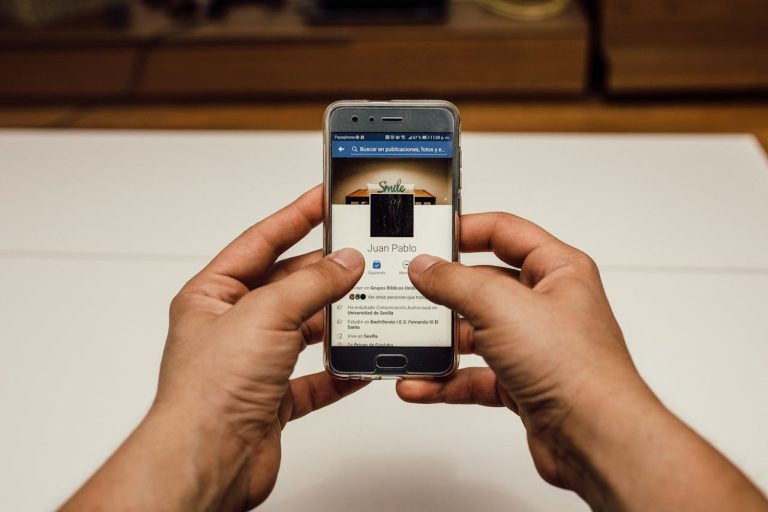 Pessoa segurando um celular com uma página do facebook aberta