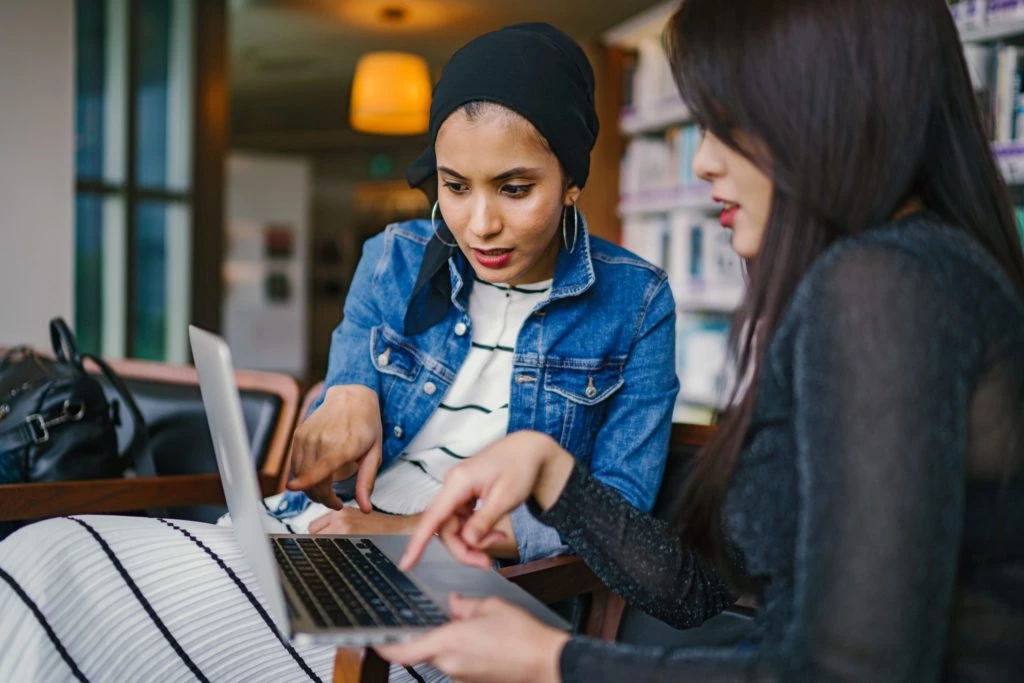 Dropshipping: O que é e como ter sua loja online 18 Duas mulheres pesquisando sobre Dropshipping na internet em frente a um notebook