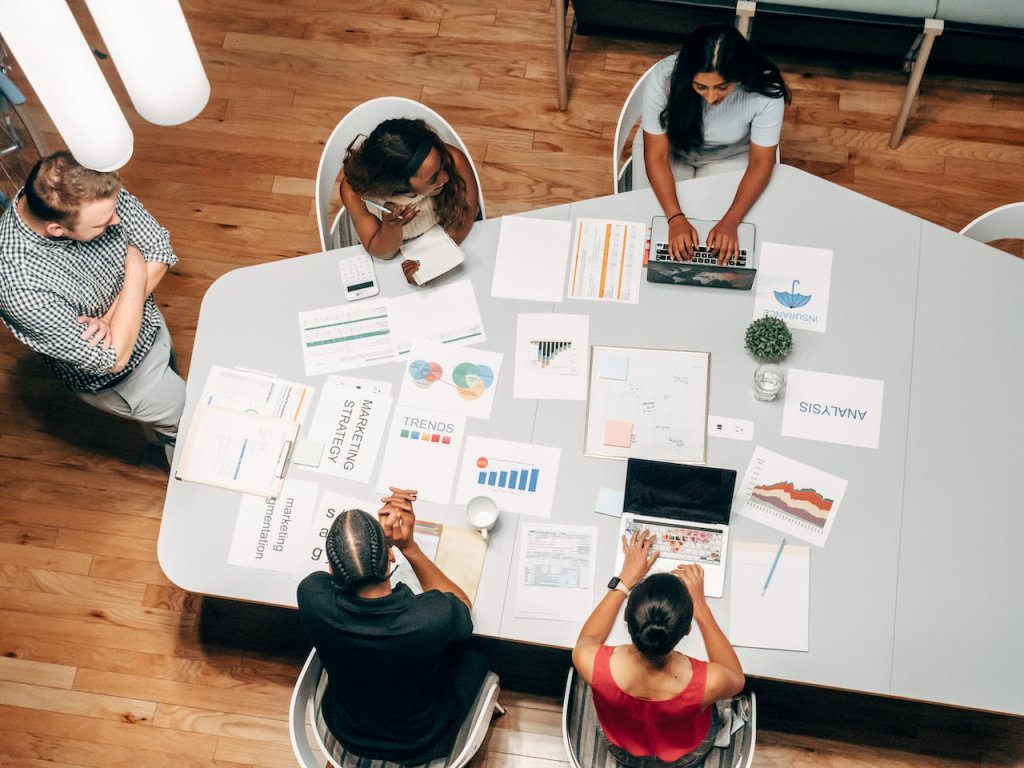 Desvendando os 4 ps do marketing: Estratégias Fundamentais para o Sucesso Empresarial 1 Pessoas em uma mesa realizando o planejamento de uma campanha de marketing com folhas sobre a mesa