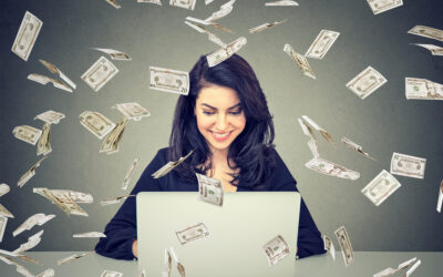Happy woman using a laptop building online business under dollar bills falling down. Money rain IT entrepreneur success economy concept produtos mais vendidos pela internet