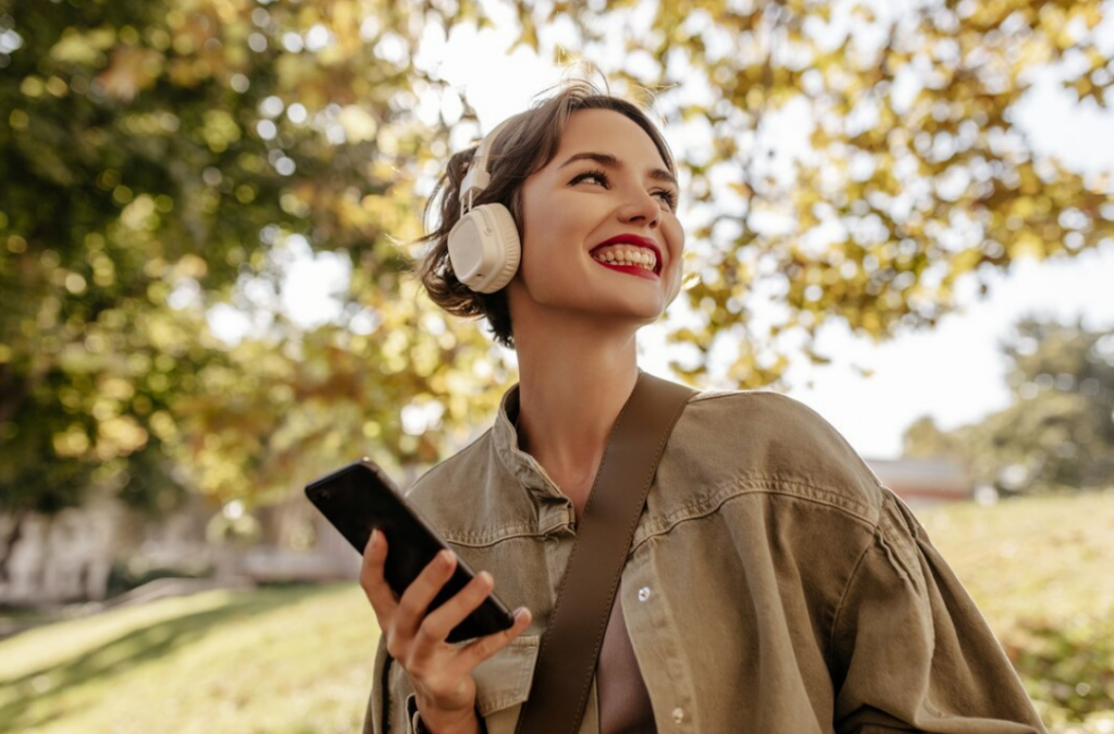Fones de ouvido bluetooth: os 11 melhores do mercado 1 Mulher passeando no parque feliz usando fones de ouvido sem fio
