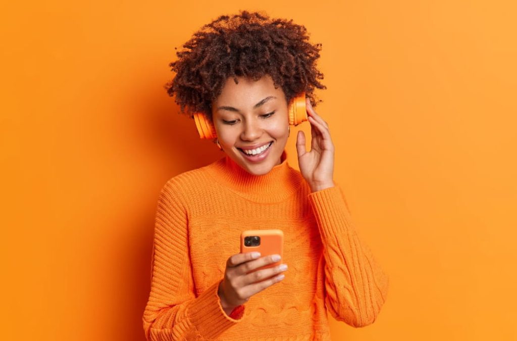 mulher escuta música em fone de ouvido utilizando seu aplicativos de música